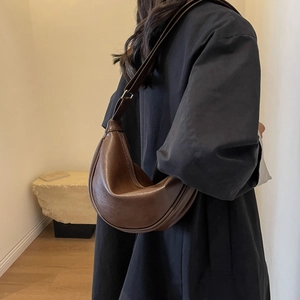 Detailed view of deep brown crescent shoulder bag with smooth texture and contrast stitching
