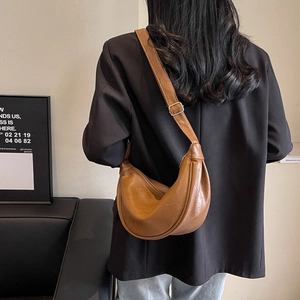 Back view of model wearing a brown retro half-moon crossbody bag with adjustable strap