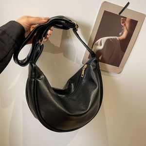 Detail of black crescent shoulder bag featuring gold-tone zipper and textured leather