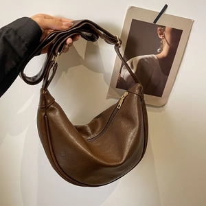 Detail of a brown crescent hobo bag showing fine leather texture and gold zipper hardware