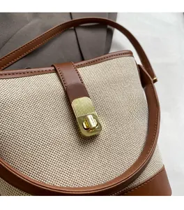 Detail of beige canvas fabric with brown leather trim and golden metal lock on bag