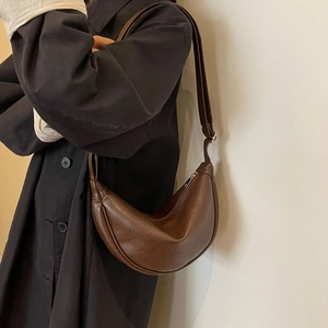 Detail view of the brown leather crescent bag with adjustable strap on a model
