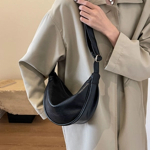Detail of a black hobo crescent bag featuring fine leather texture and adjustable strap