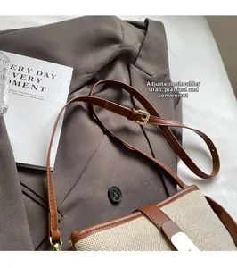 Detail of adjustable leather strap and golden buckle on a canvas crossbody bucket bag