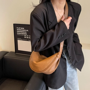 Detail view of the brown crescent bag showing soft leather texture and stylish slouchy design