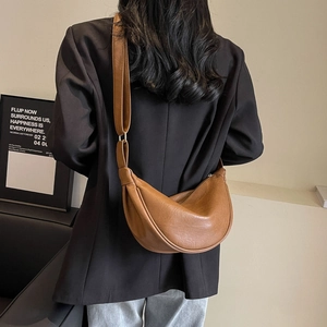 Detail view of caramel brown leather dumpling bag with adjustable shoulder strap on model