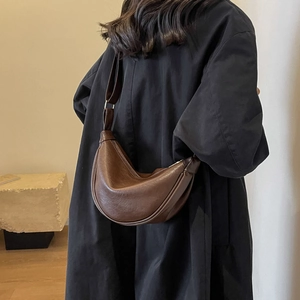 Detail of dark brown leather crescent shoulder bag with adjustable strap on a model