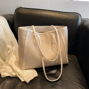 Grand sac cabas tressé minimaliste beige crème sur un canapé pour un look décontracté
