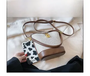 Mini bucket bag in canvas and brown leather showing compact size compared to a phone