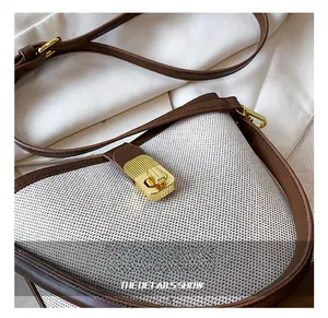 Close-up of beige woven bucket bag with brown leather trim and gold metal lock buckle