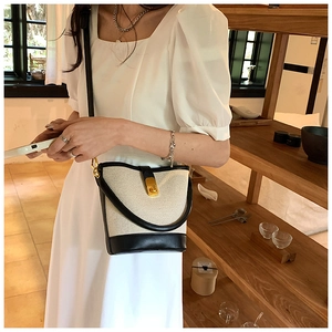 Close-up of vintage bucket bag featuring cream canvas, black leather, and gold twist lock