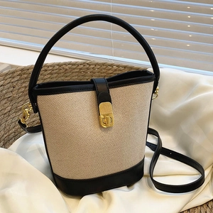 Chic two-tone canvas bucket bag with black leather trim and gold hardware closure