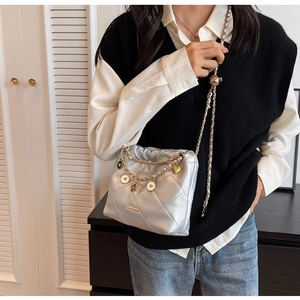 Detail of silver quilted bucket bag with gold charms and adjustable chain strap