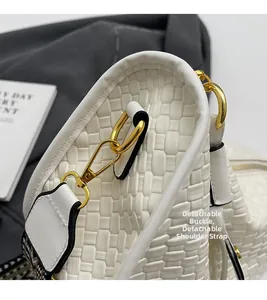 Close-up of white embossed quilted bag with golden D-ring and detachable strap