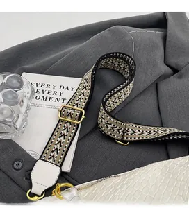 Detail of adjustable woven shoulder strap with geometric pattern and gold hardware