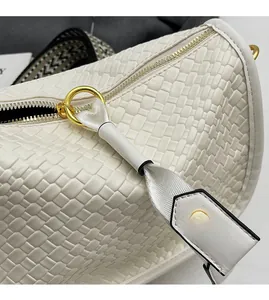 Close-up of woven white leather bag with golden hardware and smooth metal zipper