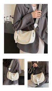 Detail of off-white woven crescent bag featuring a geometric patterned wide strap