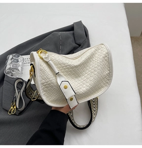 Detail of white woven hobo bag showing texture and geometric patterned wide strap