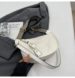 Detail of white half-moon bag featuring woven texture and jacquard woven wide strap