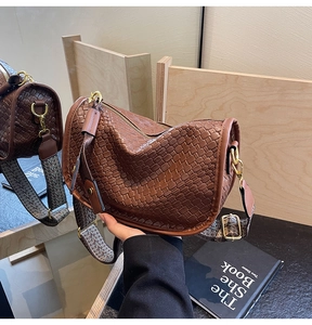 Detailed view of woven brown leather handbag featuring golden hardware and ethnic strap