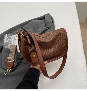 Detail of brown woven leather bag with ethnic geometric pattern wide strap and metal hardware