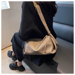 Chic taupe litchi grain leather shoulder bag with tassels shown on a model in a modern interior