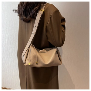 Detailed side view of beige pebble leather shoulder bag with gold hardware buckle
