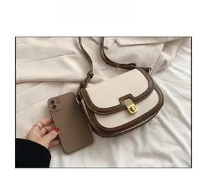 Size comparison of a contrast saddle bag next to a smartphone on white fabric