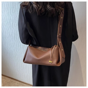 Close-up of brown pebbled leather shoulder bag with gold heart charms and grommet strap
