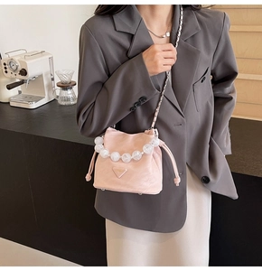 Détail du sac seau rose à cordon avec poignée en perles marbrées et bandoulière en chaîne