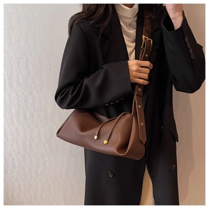 Detail of dark brown lychee leather texture and golden metal buckle on a shoulder bag
