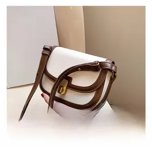 Detail of a retro cream shoulder bag featuring brown trim and a gold square clasp lock