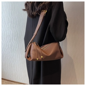Close-up of brown litchi grain leather bag with wide strap and gold eyelets detail