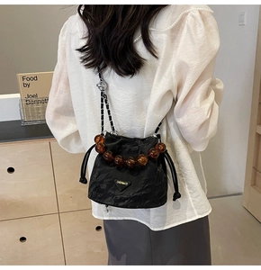 Détail du sac seau noir plissé avec poignée en perles ambrées et bandoulière chaîne