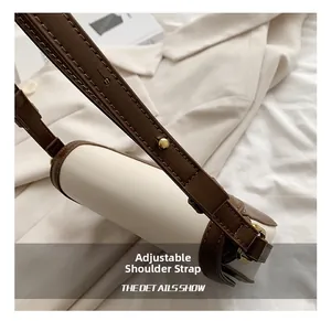 Detail of adjustable brown leather shoulder strap with premium gold hardware and stitching