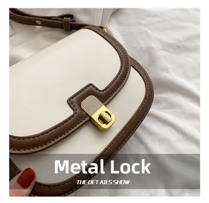Close-up of vintage brushed gold buckle on cream and brown crossbody flap bag