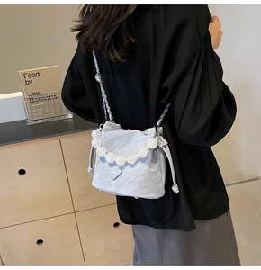 Détail du sac seau plissé bleu clair avec poignée en perles et logo triangulaire