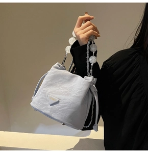 Détail d'un sac seau plissé bleu clair avec poignée en perles marbrées et chaîne métal