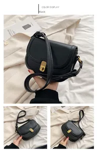 Detail view of the black crossbody bag showing its glossy leather and golden metal clasp