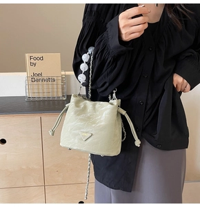 Détail du sac seau plissé vert pistache avec chaîne décorative et poignée perlée