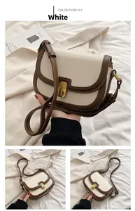 Detail view of cream saddle crossbody bag with brown trim and vintage metal clasp
