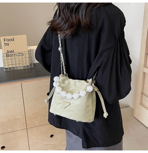 Détail du sac seau vert pistache avec poignée en perles blanches et fermeture cordon