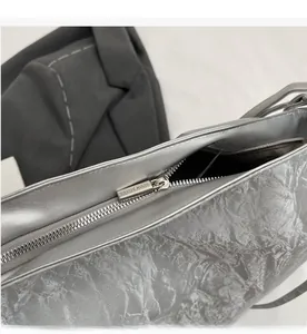 Detail of smooth silver metal zipper and pleated metallic fabric on a large tote bag