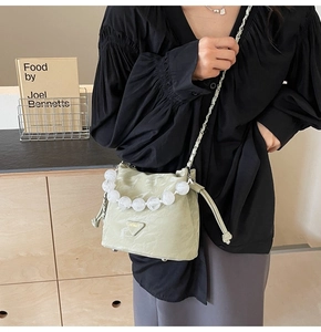 Détail du sac seau plissé vert pistache avec poignée en perles acryliques et chaîne