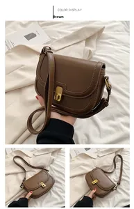 Detail of a brown leather saddle bag with a golden metal lock and adjustable strap