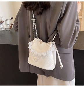 Détail du sac seau blanc matelassé avec grande poignée en perles et plaque logo