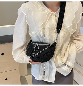 Detail of black pleated half-moon bag featuring silver chain and large ring zipper