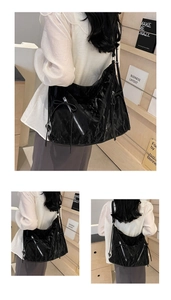 Detail view of large black pleated tote bag with silver zippers and bow accents