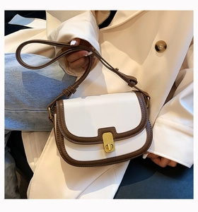 Detail of retro white and brown leather shoulder bag with gold clasp and adjustable strap