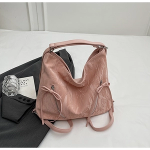 Detailed close-up of pink ruched leather bag featuring metal zippers and bow accents